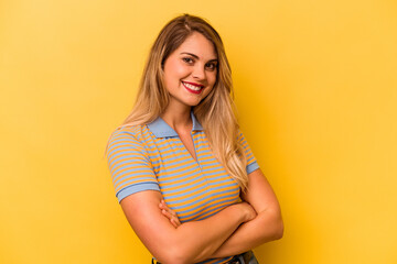 Young caucasian woman isolated on yellow background who feels confident, crossing arms with determination.