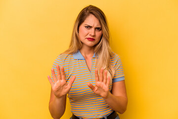 Young caucasian woman isolated on yellow background rejecting someone showing a gesture of disgust.