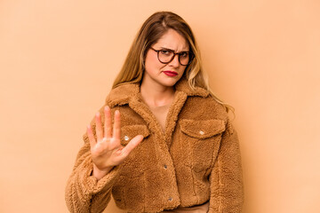Young caucasian woman isolated on beige background rejecting someone showing a gesture of disgust.
