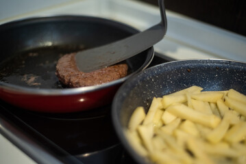 Cooking meat and fries in oily saucepan   