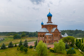 Drone view of Church of St. Nicholas and St. George (Nikolo-Georgievskaya, 1894, Russian style) on cloudy summer day. Smogiri village, Smolensk Oblast, Russia.