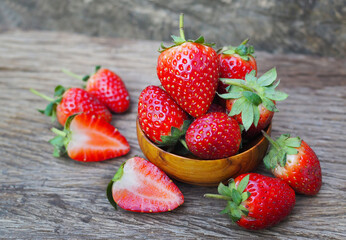 Ripe red strawberries in wood bowl on old wooden table background