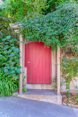 Fototapeta na wymiar Arched wooden red door gate with arbor roof at the front in San Francisco, California