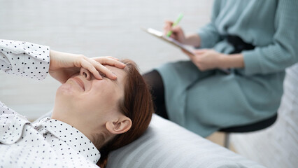 Caucasian woman crying while lying on the couch at a session with a psychologist.