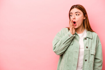 Young caucasian woman isolated on pink background being shocked because of something she has seen.