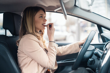 Business  woman fixing her makeup while waiting in the car.Using lipstick.