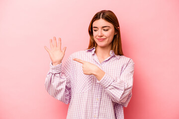 Young caucasian woman isolated on pink background smiling cheerful showing number five with fingers.