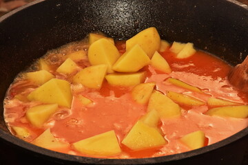 food cooking in stew pot ,tocana, ceaun,potatoes in orange sauce,soup