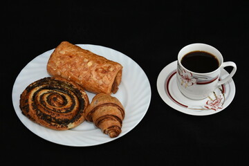 porcelain platter with Croissants, and a cup of coffee on black background