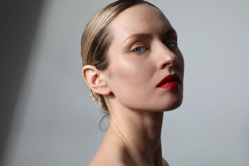 Beauty face. Young woman with fresh glowing skin and red lips posing at studio. 