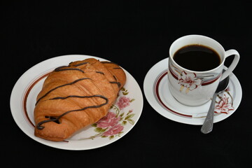 porcelain platter with Croissants, and a cup of coffee on black background