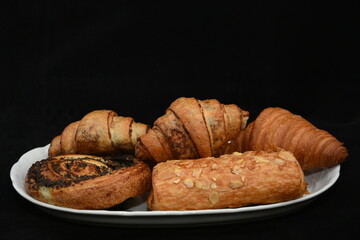 Breakfast.  porcelain platter  with Croissants, donuts. crullers  on red  background