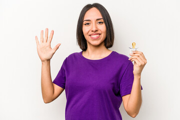 Young hispanic pregnant woman holding pacifier isolated on white background smiling cheerful...
