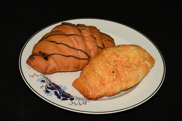 Breakfast.  porcelain platter  with Croissants, donuts. crullers  on red  background