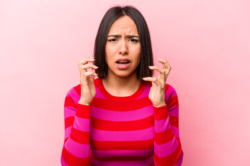Young hispanic woman isolated on pink background upset screaming with tense hands.