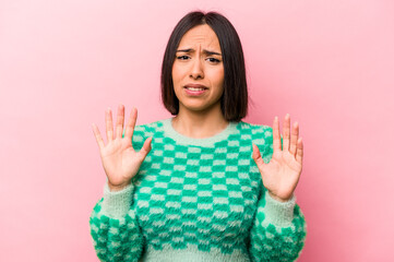 Young hispanic woman isolated on pink background rejecting someone showing a gesture of disgust.