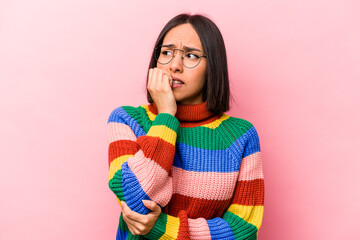 Young hispanic woman isolated on pink background biting fingernails, nervous and very anxious.