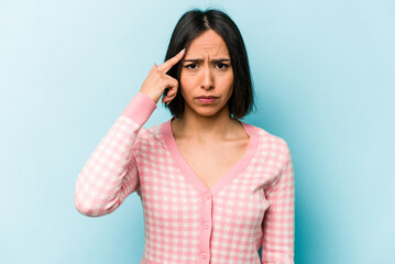 Young hispanic woman isolated on blue background pointing temple with finger, thinking, focused on a task.