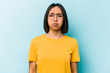 Fototapeta Young hispanic woman isolated on blue background blows cheeks, has tired expression. Facial expression concept. obraz
