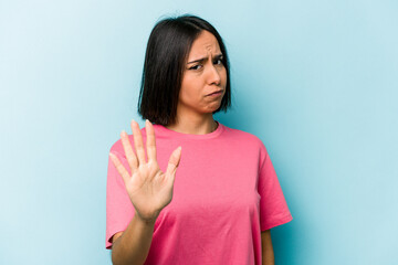 Young hispanic woman isolated on blue background rejecting someone showing a gesture of disgust.