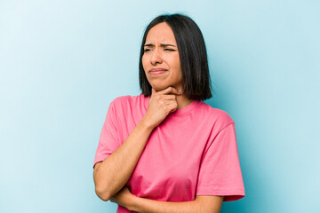 Young hispanic woman isolated on blue background suffers pain in throat due a virus or infection.