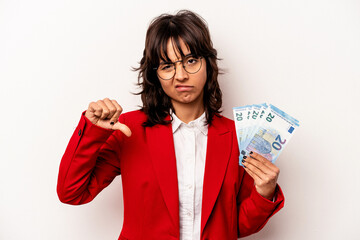 Young business hispanic woman holding banknotes isolated on white background showing a dislike gesture, thumbs down. Disagreement concept.