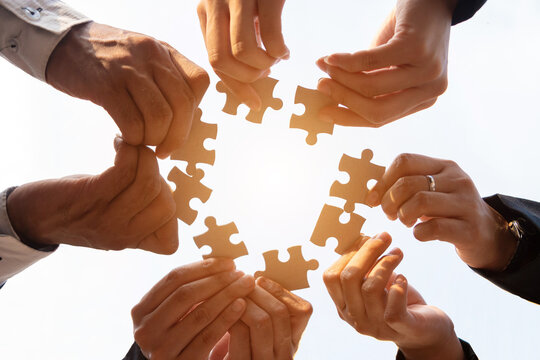 The hand of a businessman holding a paper jigsaw And solving the puzzle together. The business team assembles a jigsaw puzzle. A business group wishing to bring together the puzzle pieces