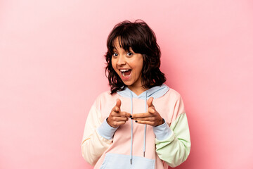 Young hispanic woman isolated on pink background pointing to front with fingers.