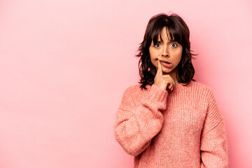 Young hispanic woman isolated on pink background looking sideways with doubtful and skeptical expression.