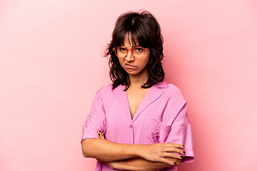 Young hispanic woman isolated on pink background frowning face in displeasure, keeps arms folded.