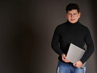 Latin man carrying a laptop, isolated on gray background