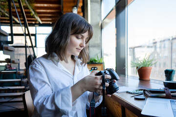 woman photographer works in coworking space. The girl takes pictures on the camera in a cafe.