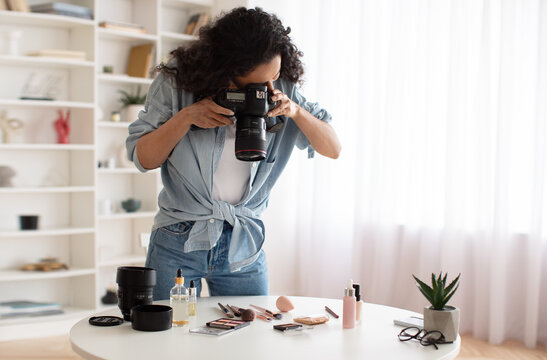 Blogger Woman With Camera Taking Photos Of Makeup Products Indoors