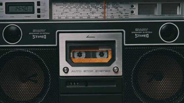 Vintage audio cassette rotates in Tape Recorder. Old yellow audiocassette tape with blank label in retro player is spinning and playing. Close-up. Call recording, playback, rotation of reel with tape