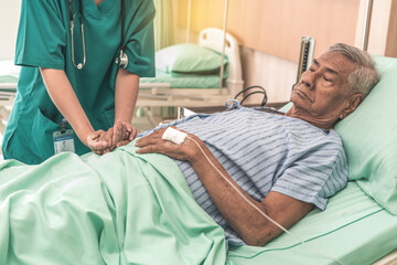 elderly man is sick, lying in bed, giving saline water. A nurse comes to take care of him in the hospital.