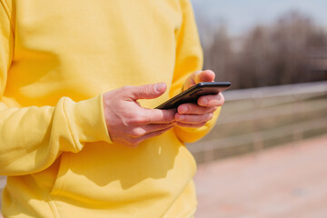 A man in a yellow hoodie uses a smartphone. Hands type on the phone. A person makes an order of...
