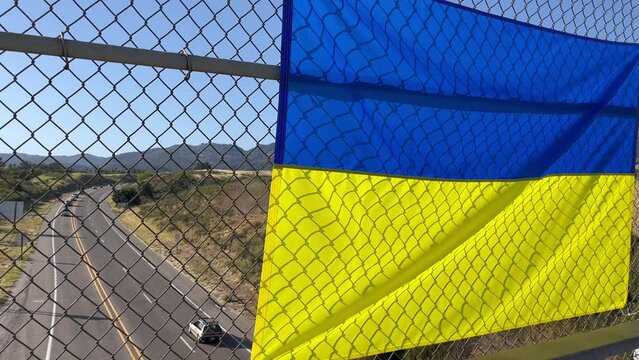 Ukraine flag overlooking highway with a few cars crossing