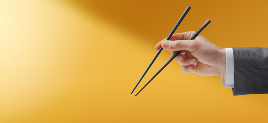 Man holding chopsticks on yellow background