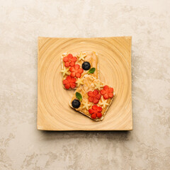 Sweet sandwiches peanut butter with fruits, berries with honey on a wooden board, top view. Healthy tasty breakfast.