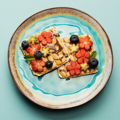 Sweet sandwiches peanut butter with fruits, berries with honey on a plate, top view. Healthy tasty breakfast.