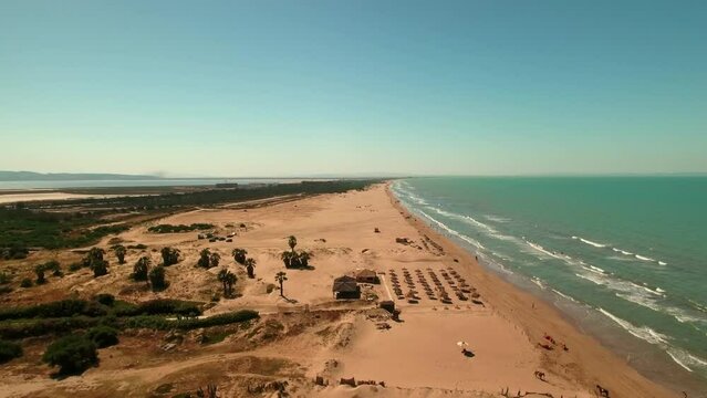 Aerial Shot Of Tourists Exploring Sea At Beach On Vacation, Drone Flying Forward Towards Shades Arranged On Landscape - Djerba, Tunisia