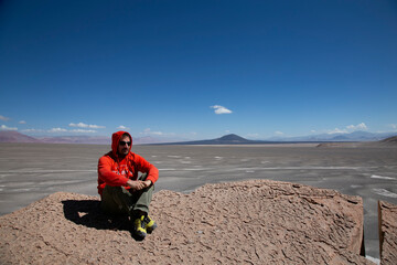 Lonely white male tourist poses sitting for photograph in the Puna de Catamarca, Argentina