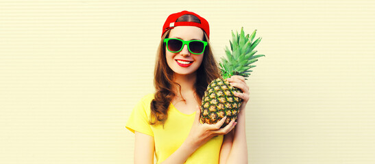 Summer portrait of happy smiling woman with pineapple wearing red baseball cap, sunglasses on white background