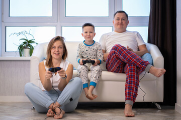 Young family with a child playing video games at home on the couch