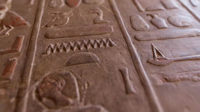 Antique stone wall with carved ancient Egyptian hieroglyphs. Close shot of Egyptian hieroglyphs on the wall in Hatshepsut temple. Shallow DOF, gimbal shot