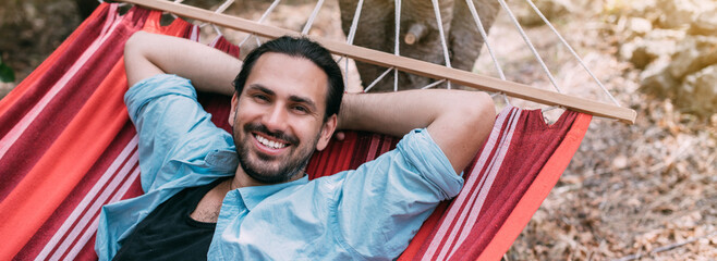 Young man is resting in a hammock in the garden