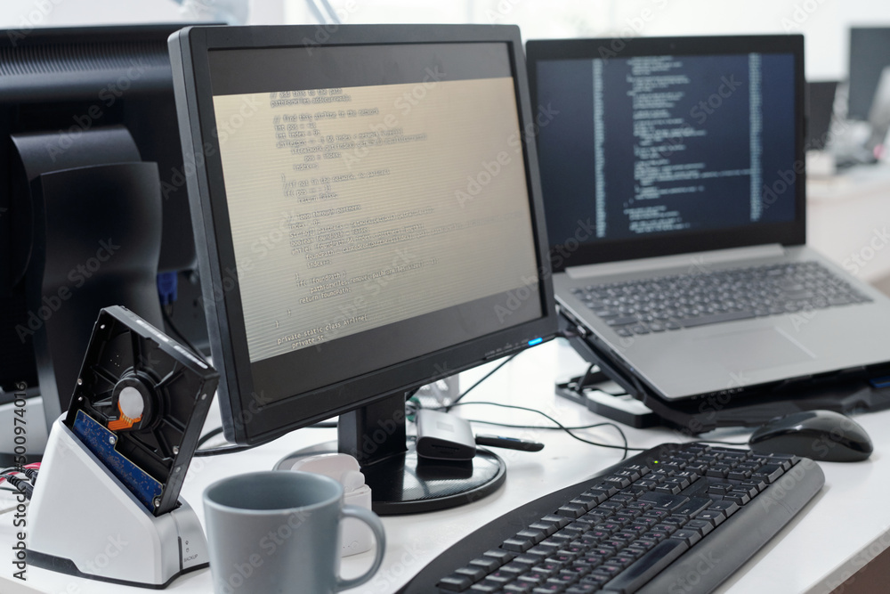 Aufkleber Computer monitor with decoded data on screen and laptop of contemporary programmers in openspace office or bureau