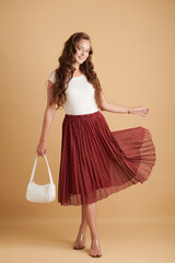 Full-length portrait of cheerful young woman wearing long flowing polka dot skirt for summer day