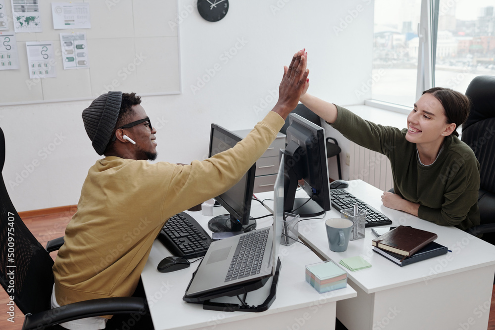 Aufkleber Two young successful programmers congratulating one another with decoding data while giving each other high-five over computer monitor
