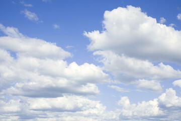 Blue sky with white clouds illuminated by daylight. The background of the blue sky. Free space for text.